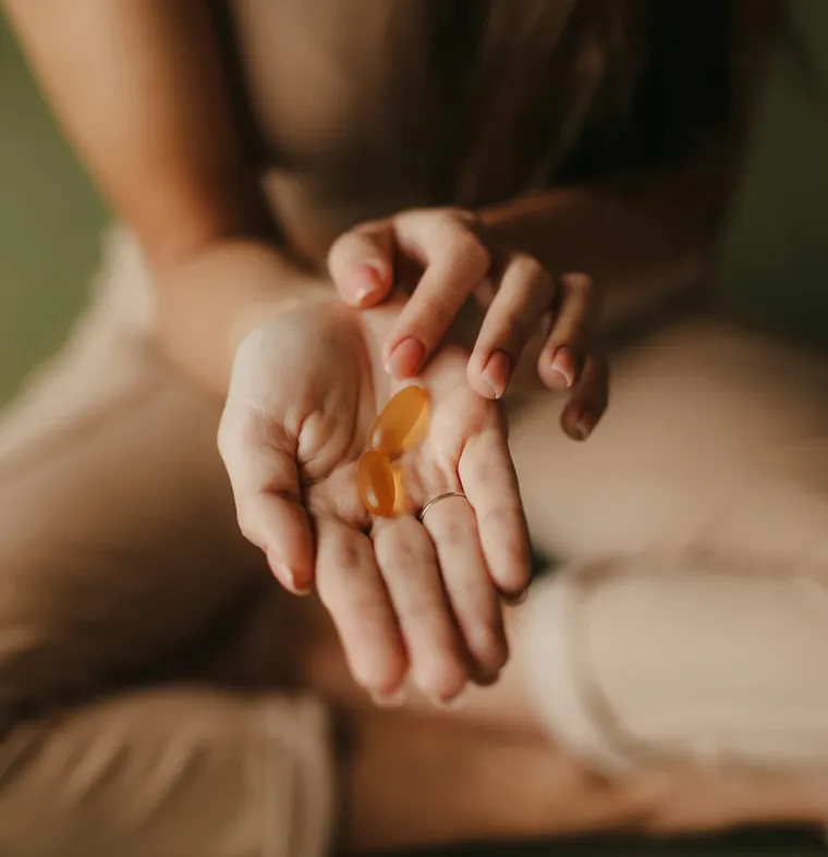 A person holding omega-style softgel supplements in an open palm, representing nutritional support at Fort Walton Beach Chiropractic